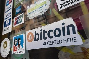 A shop window plastered with stickers denoting forms of accepted payment, including a sign for bitcoin.