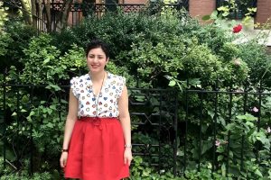 Alaleh Azhir stands in front of a wrought iron fence and shrubbery.