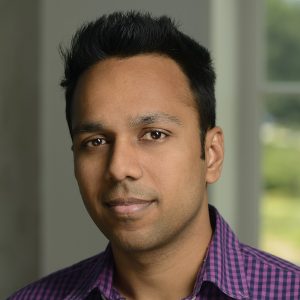 A headshot of Abhishek Jain wearing a purple and blue checkered shirt