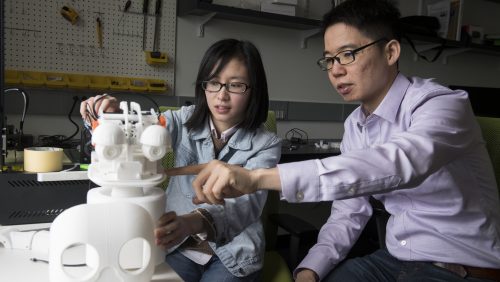 Chien-Ming Huang and a student work in a robotics lab.
