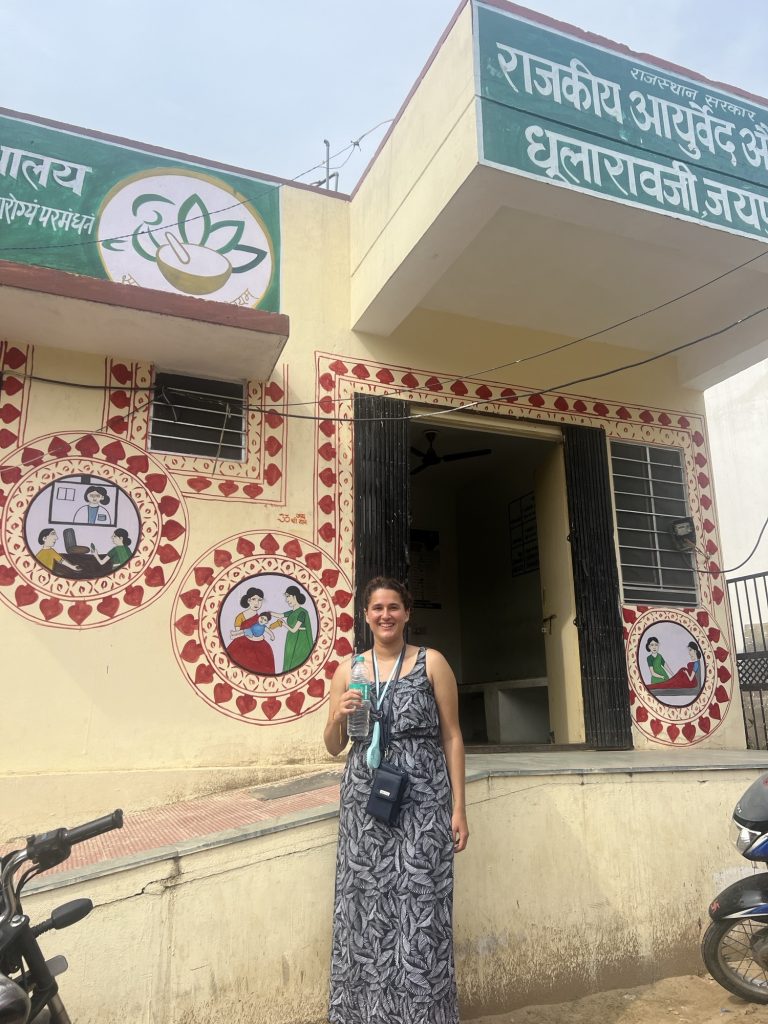 Amanda Ferber holding a water bottle outside of a clinic providing botanic therapeutics in a Dhula village in Rajasthan.