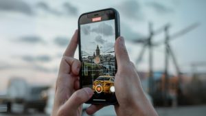 Someone holding a smartphone records footage of a city scene.