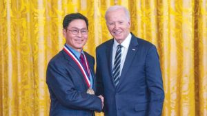 Wearing a medal, Jeong Kim poses with President Biden.