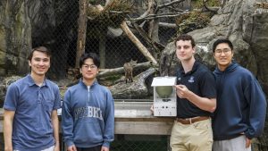 Students from the Johns Hopkins Multidisciplinary Engineering Design course showcase their bobcat feeding system in front of the bobcat enclosure at the Maryland Zoo.