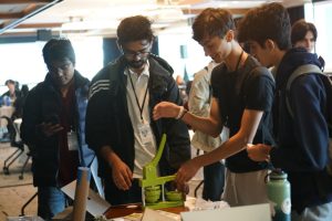 Students gather around a plastic contraption.